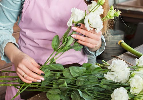 A woman handles the leaves of an average-sized floral bouquet