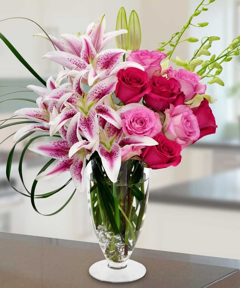 Pedestal vase filled with lilies, roses and orchids